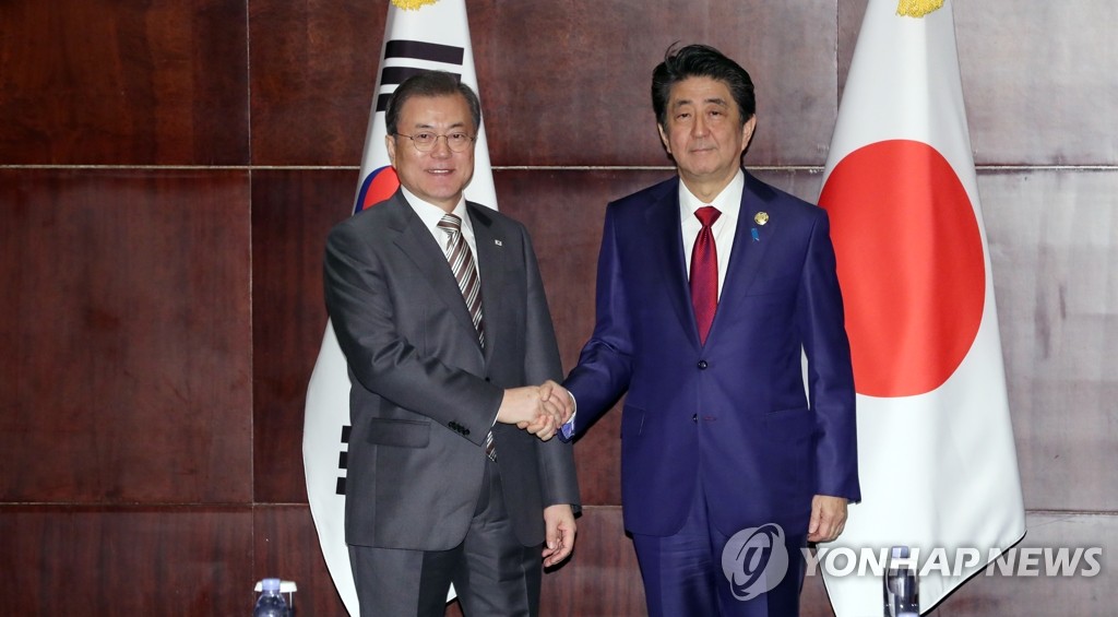 12月24日，在成都，韩国总统文在寅（左）和日本首相安倍晋三握手合影。 韩联社
