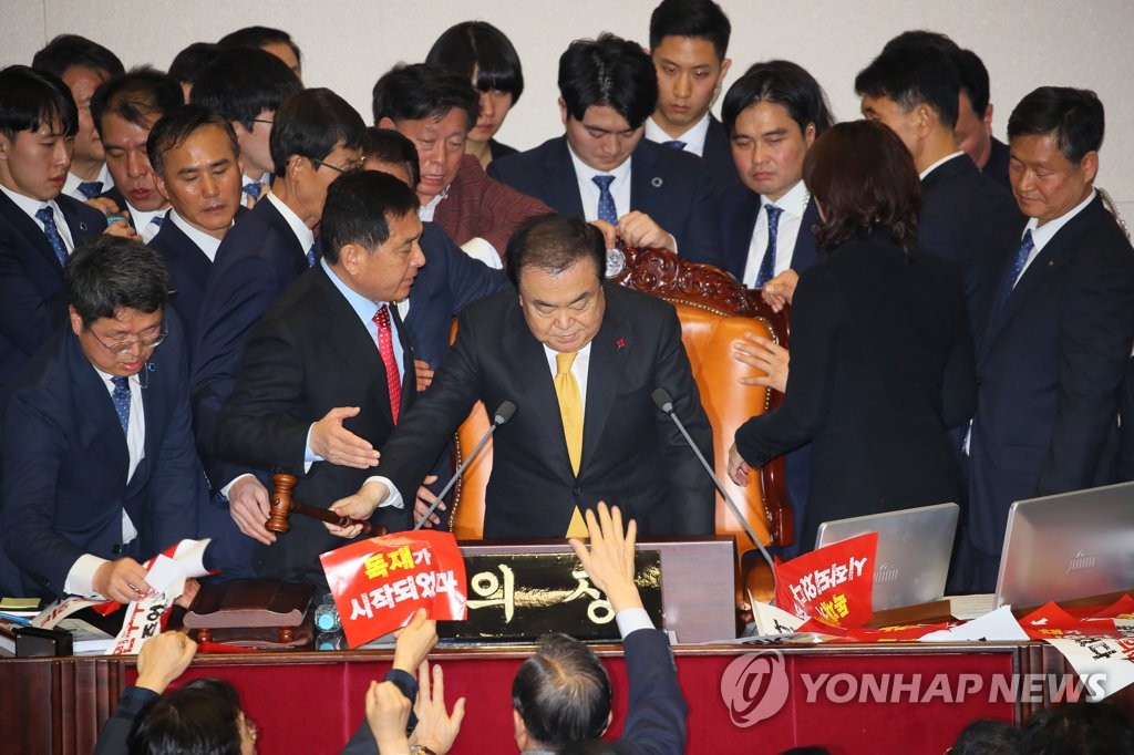 12月27日，在韩国国会，国会议长文喜相在自由韩国党议员的阻挡下为《公职选举法》修订案表决结果落锤定音。 韩联社