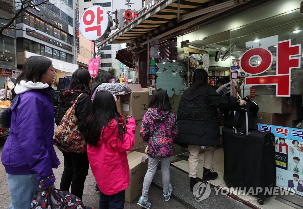 资料图片：1月27日，在首尔明洞一家药店，外国游客排队购买口罩。 韩联社