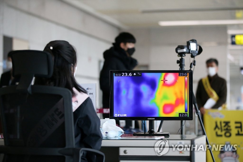 1月30日下午，在庆尚南道浦项机场，工作人员注视测温仪筛查发热旅客。 韩联社