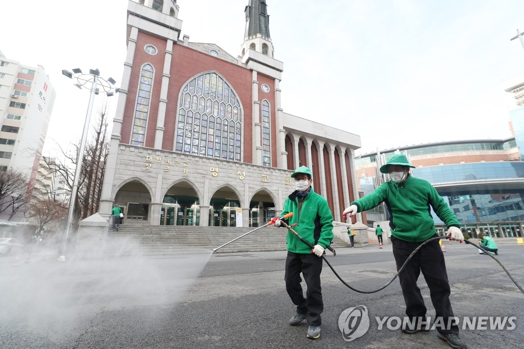 资料图片：2月26日上午，在首尔市江东区的明声教会门口，防疫人员正在进行喷雾消毒。 韩联社