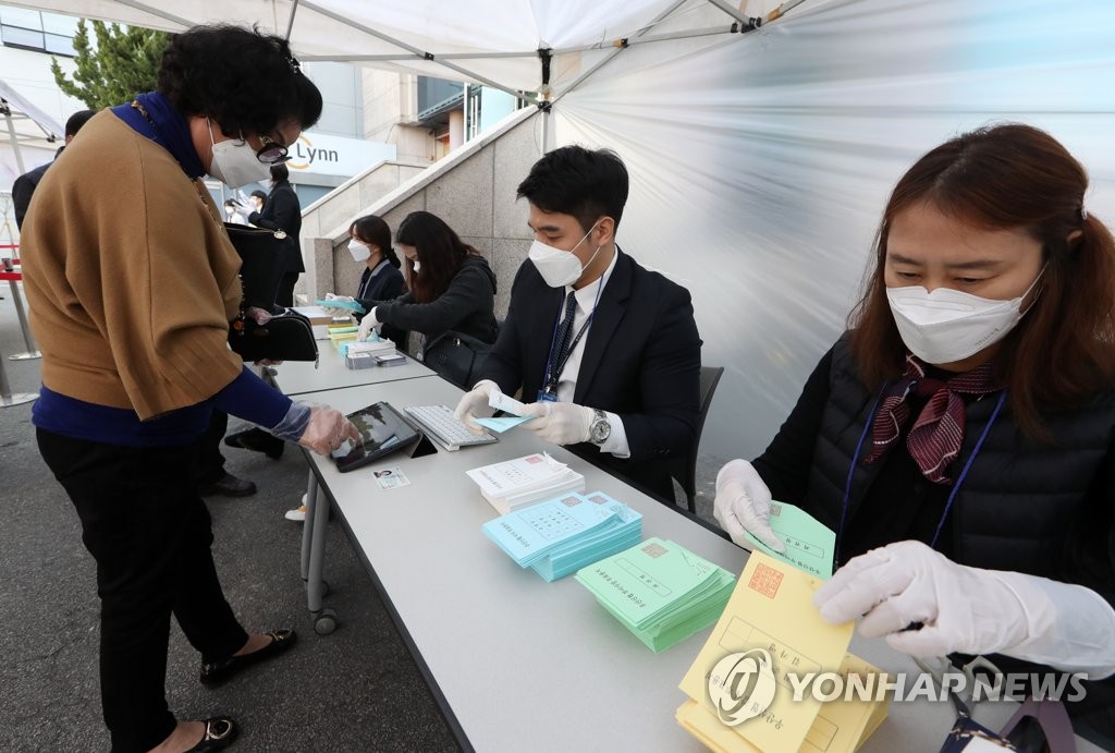 3月25日，在光州市光山区牛山洞一家信用合作社门前，一名选民佩戴口罩和手套参与干部选举投票。 韩联社