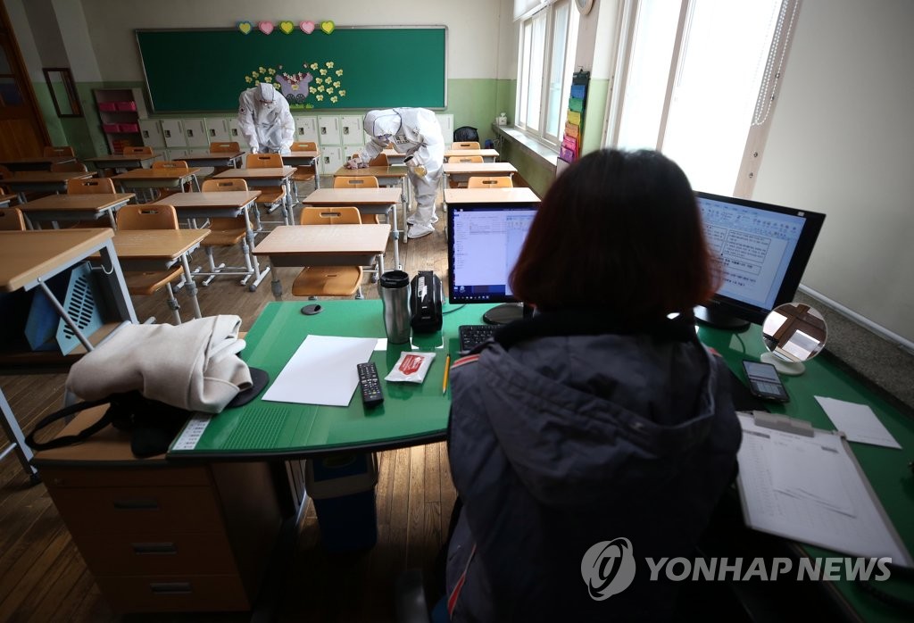 资料图片：4月7日，在大邱南山小学一间教室，一位女教师准备线上开学。教室里还有韩国陆军第五十师的官兵进行防疫消毒。 韩联社