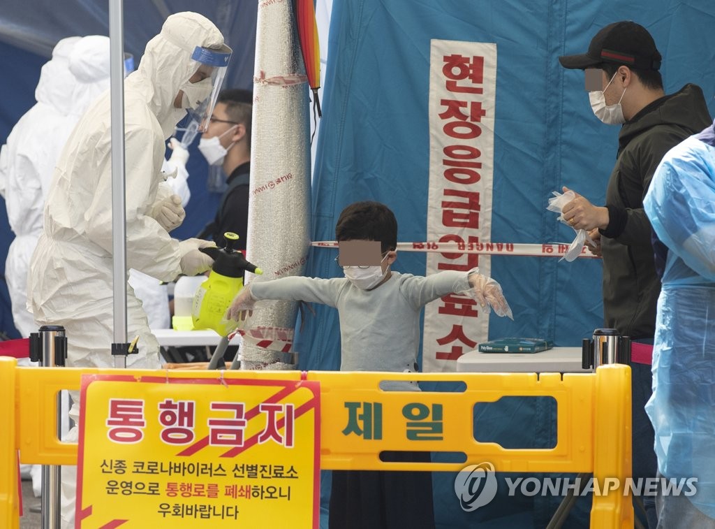 资料图片：一名儿童在筛查站接受新冠病毒检测。 韩联社