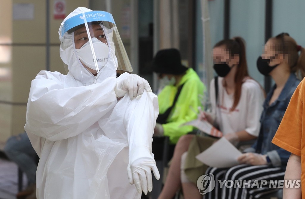 资料图片：医疗人员穿着防护服准备进行病毒检测。 韩联社