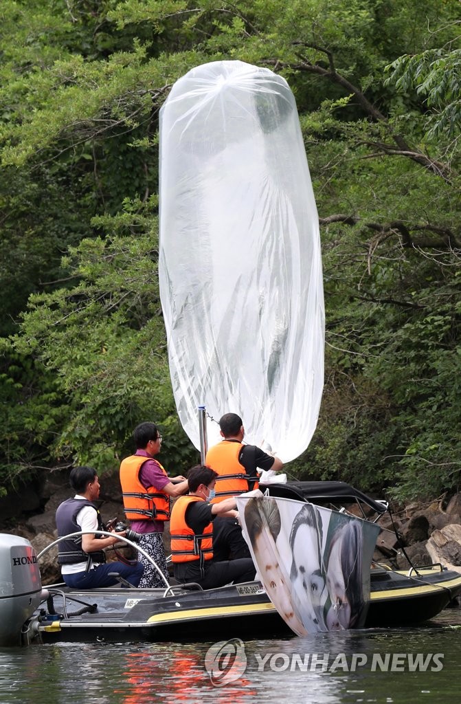 6月23日，在韩国江原道洪川郡的一座山，警察们正在打捞脱北者团体前一晚对朝散布传单时使用的气球。气球尺寸2-3米，垂挂着朝鲜国务委员会委员长金正恩家族照片。 韩联社