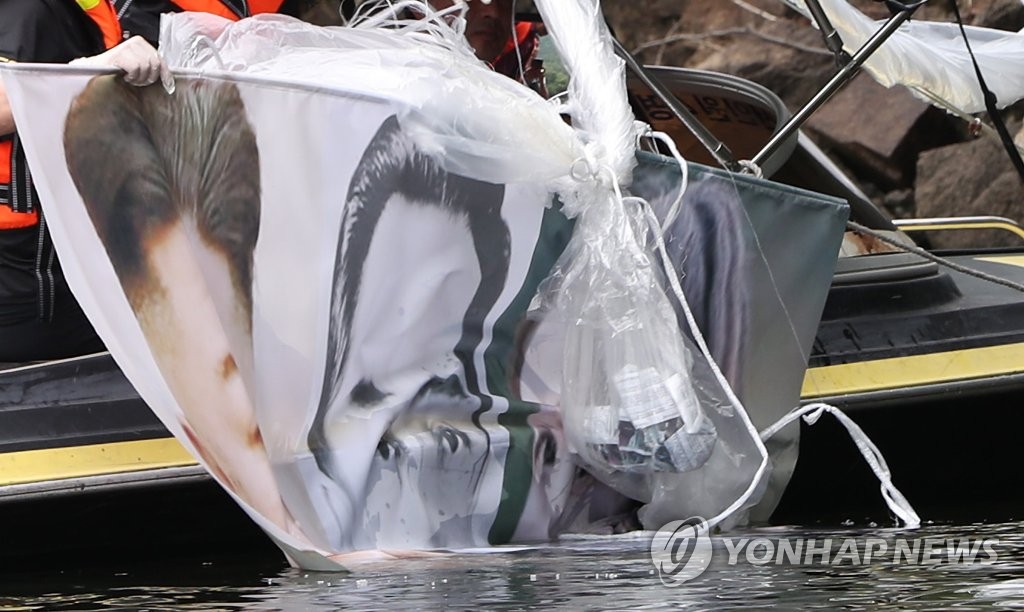 6月23日，在韩国江原道洪川郡的一座山，警察们正在打捞脱北者团体前一晚对朝散布传单时使用的气球。气球尺寸2-3米，垂挂着朝鲜国务委员会委员长金正恩家族照片。 韩联社