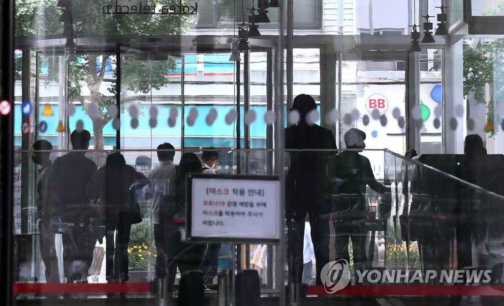 资料图片：7月2日，受新冠疫情影响，位于首尔光化门的一家企业采取在家办公等措施。图为职员们离开办公楼。 韩联社