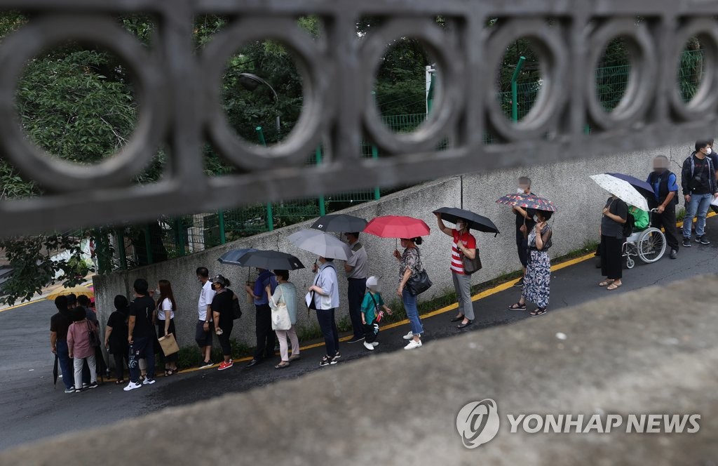 资料图片：7月28日，在首尔中区的中国驻韩大使馆领事部前，人们排长队等待办签证。 韩联社