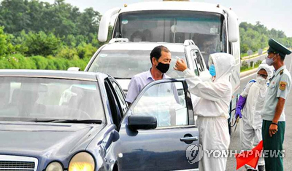 资料图片：据朝鲜劳动党机关报《劳动新闻》7月29日报道，朝鲜要求全体居民出门必须佩戴口罩并对手进行严格消毒，防控新型冠状病毒（COVID-19）。图为医疗人员在平壤市万景台区的一条公路上为过往车辆司机测量体温。 韩联社/《劳动新闻》官网截图（图片仅限韩国国内使用，严禁转载复制）