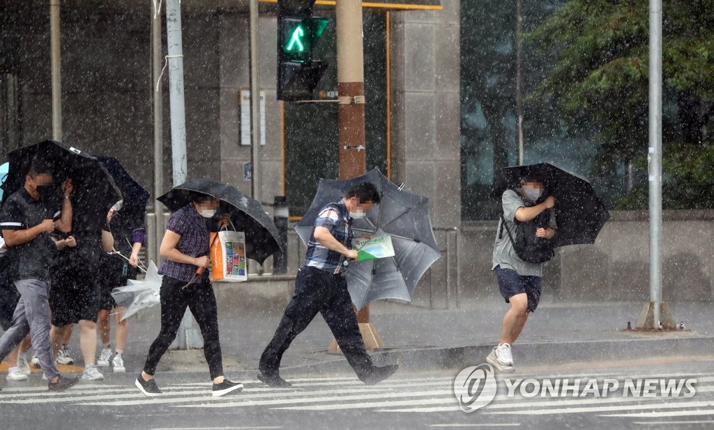 8月26日，在全罗南道木浦市木浦火车站前的一处人行横道，行人们撑伞冒雨前行。受台风“巴威”影响，木浦市遭遇强风暴雨天气。 韩联社
