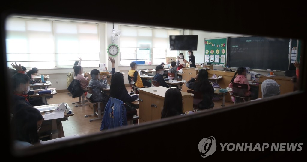 资料图片：在一所小学，学生们戴着口罩上课。 韩联社