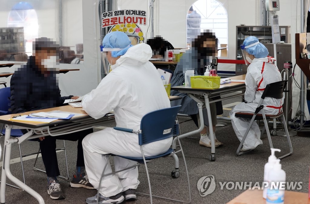 资料图片：在一处筛查诊所，医疗人员帮市民填写表单。 韩联社