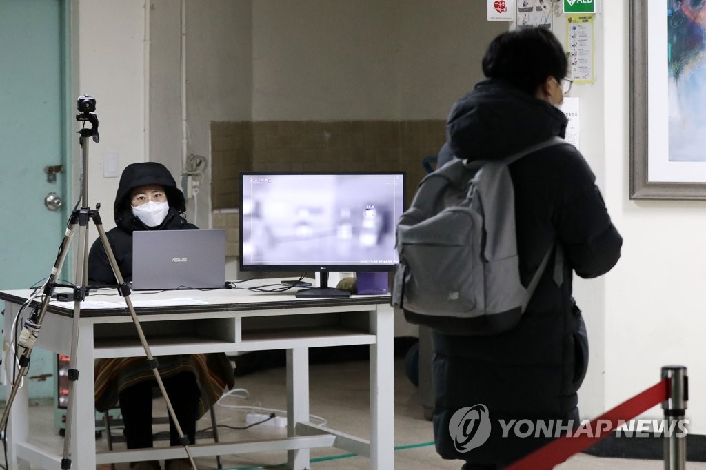 资料图片：2020年12月3日，在首尔钟路区的景福高中，考生在进考场前接受体温检测。 韩联社/联合采访团