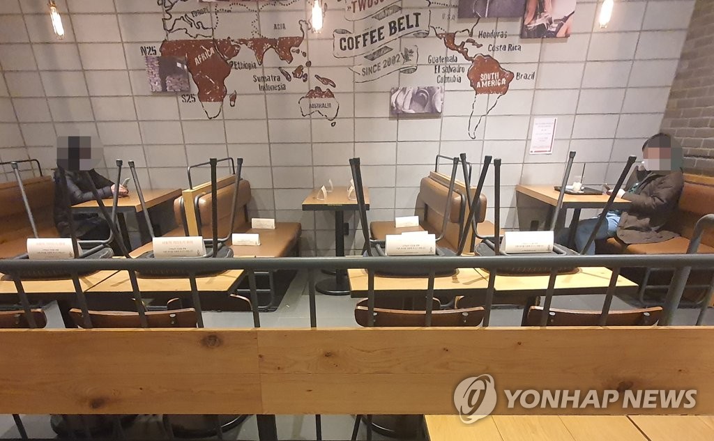 资料图片：保持人际距离的咖啡店顾客 韩联社