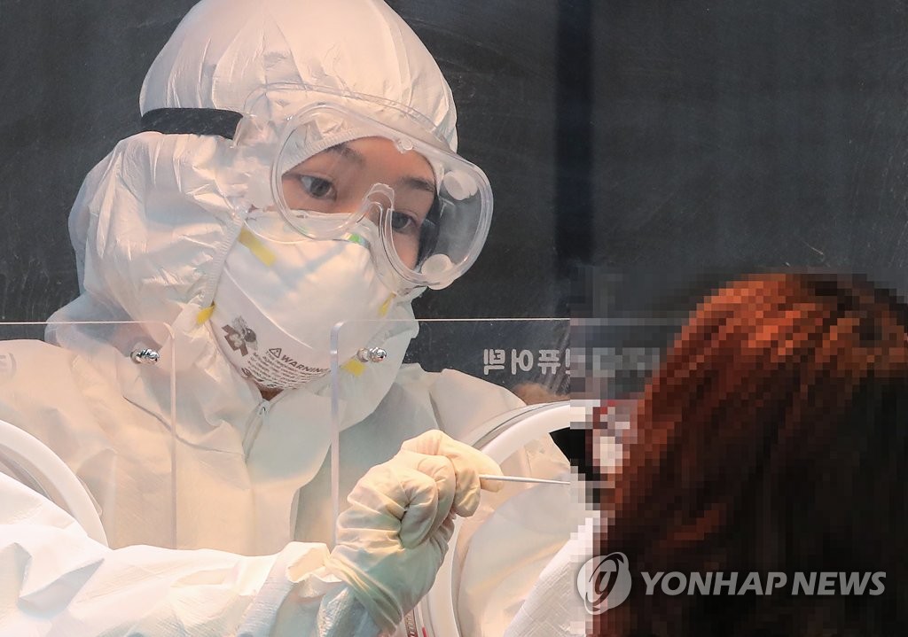 资料图片：医务人员在临时筛查诊所进行病毒检测。 韩联社