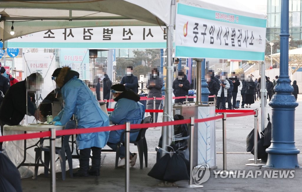 资料图片：2月3日上午，在设于首尔火车站广场的临时筛查诊所，市民们排起长龙等待接受新冠病毒检测。 韩联社