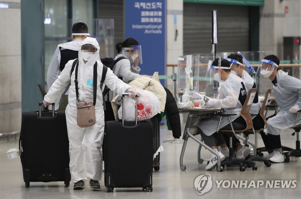 资料图片：2月5日，在仁川国际机场，外籍旅客身穿防护服离开国际到达大厅。 韩联社
