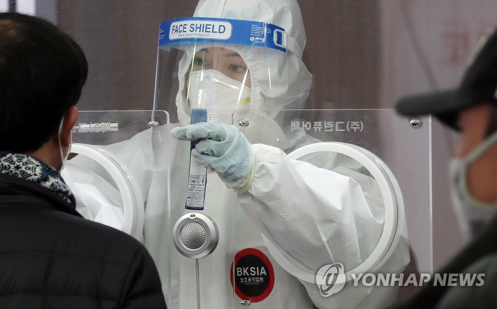 资料图片：2月7日，在设于首尔火车站广场的筛查诊所，防疫人员对市民进行病毒检测。 韩联社