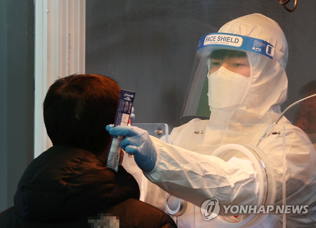资料图片：在一处筛查诊所，防疫人员对市民进行病毒检测。 韩联社