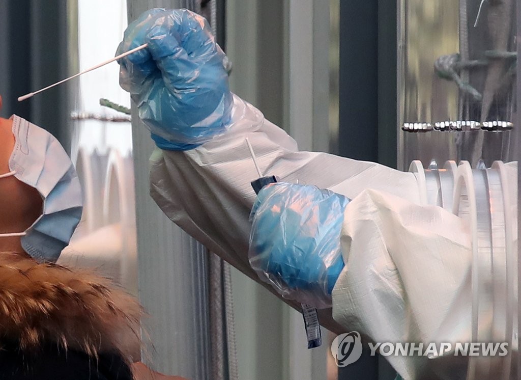 资料图片：2月19日，在设于首尔火车站广场的临时筛查诊所，医务人员采集鼻咽试子进行新冠病毒检测。 韩联社