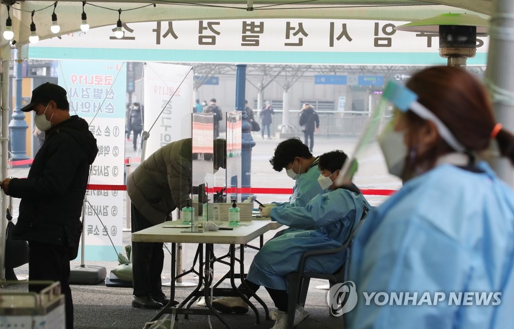 资料图片：2月20日，在设于首尔火车站广场的临时筛查诊所，市民等待接受病毒检测。 韩联社
