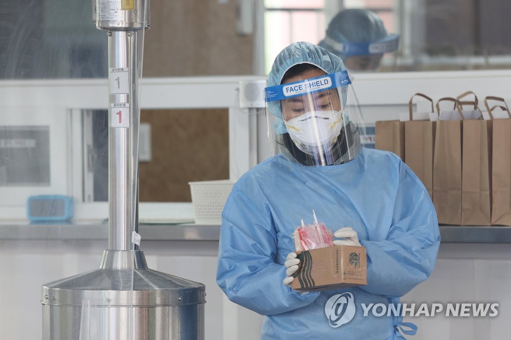 2月22日下午，在首尔市铜雀区卫生所，一名护士手持试剂盒准备进行核酸检测采样。 韩联社