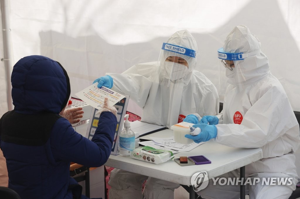 资料图片：在一处筛查诊所，医务人员对市民介绍病毒检测。 韩联社