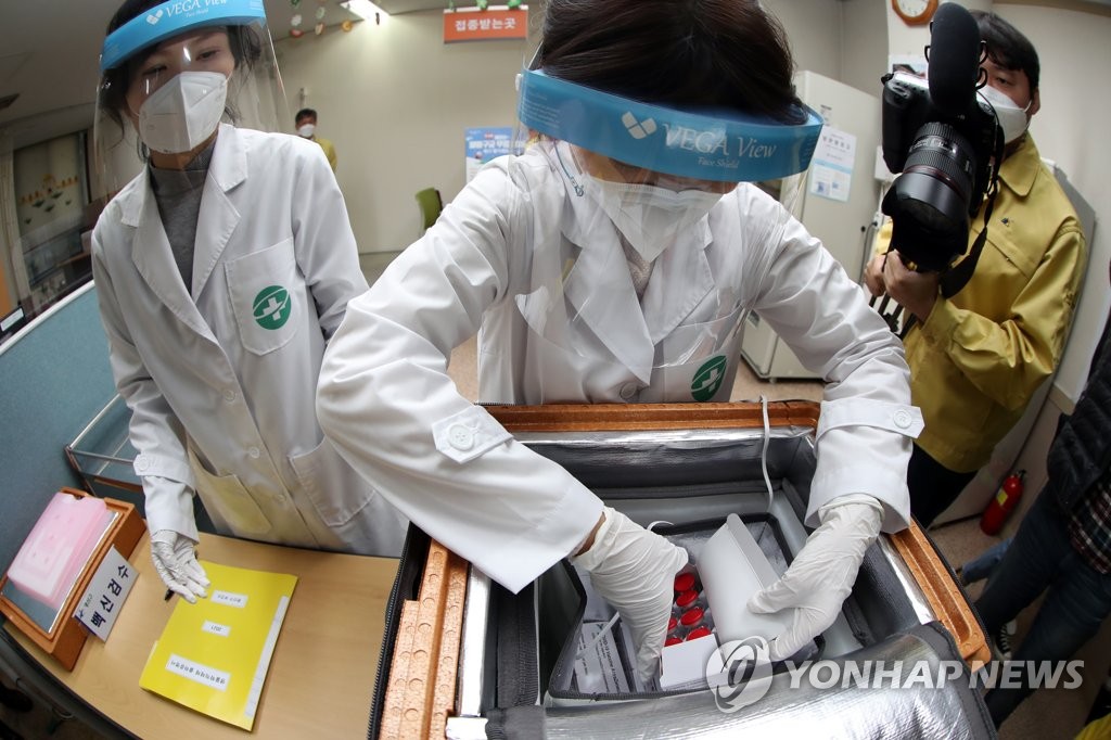 2月25日，在光州市一家卫生站前，医务人员验收刚刚运抵的阿斯利康新冠疫苗。 韩联社