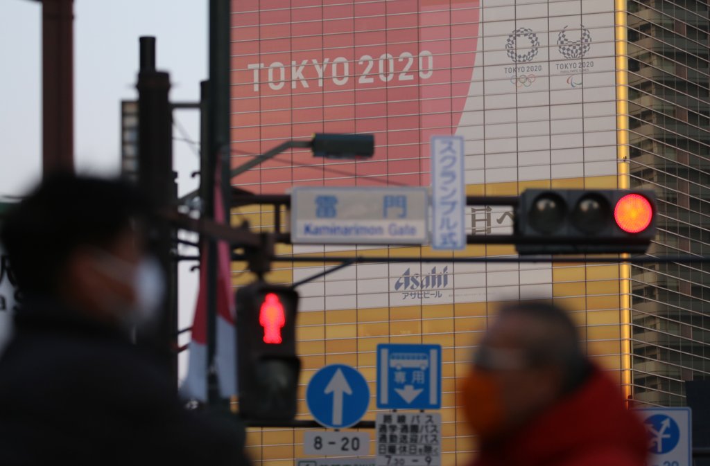 资料图片：2月20日，在日本东京市墨田区一建筑物上张贴的奥运会宣传广告前，一交通信号灯亮起红灯。 韩联社