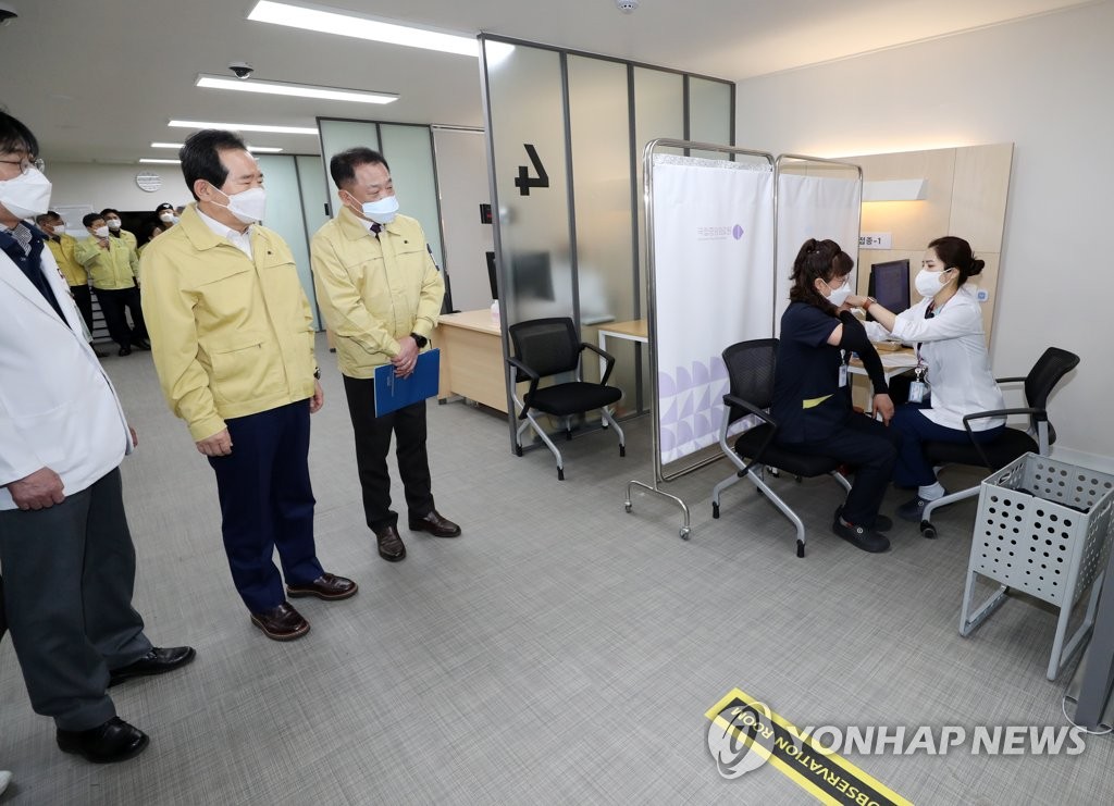2月27日，韩国务总理丁世均（左二）视察接种现场。 韩联社