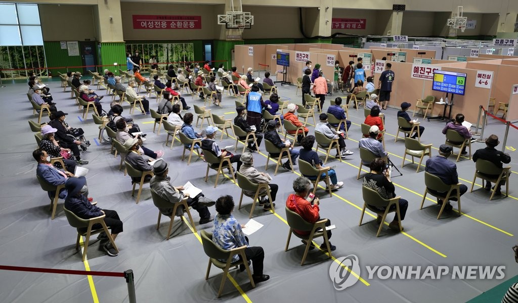 资料图片：市民在新冠疫苗预防接种中心等待接种疫苗。 韩联社