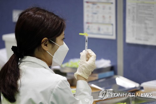 资料图片：6月14日上午，在光州市北区，一处预防接种中心，一名医务人员将一瓶新冠疫苗分成两针。 韩联社