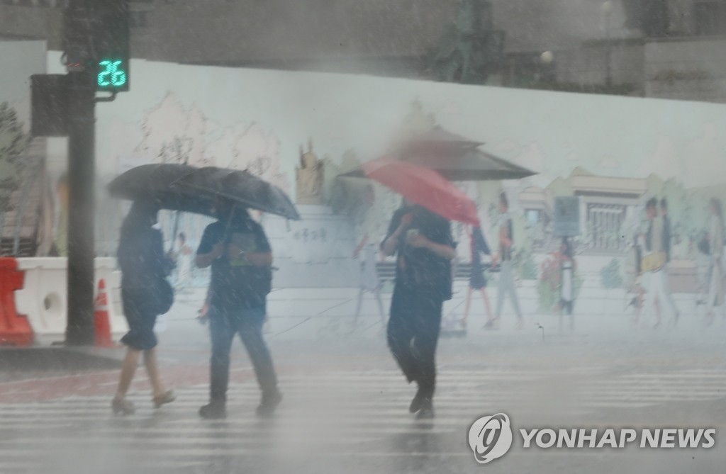 6月23日，在首尔光化门广场，撑伞的行人步履匆匆。 韩联社