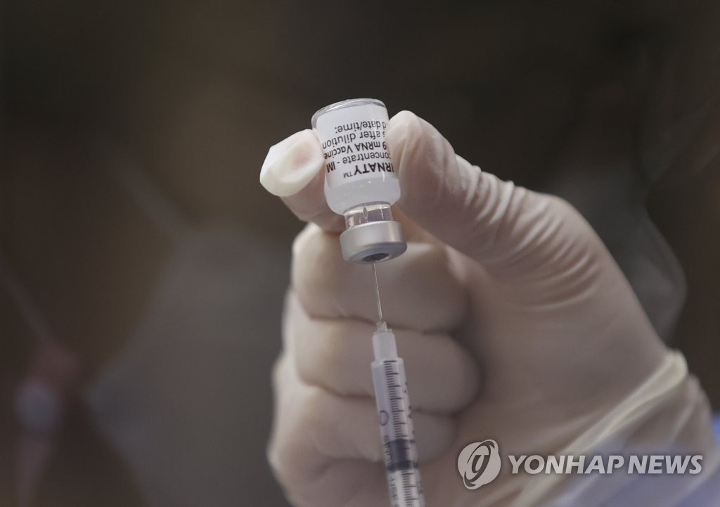 资料图片：6月29日，在首尔铜雀区的预防接种中心，医务人员用注射器抽吸辉瑞疫苗药液。 韩联社