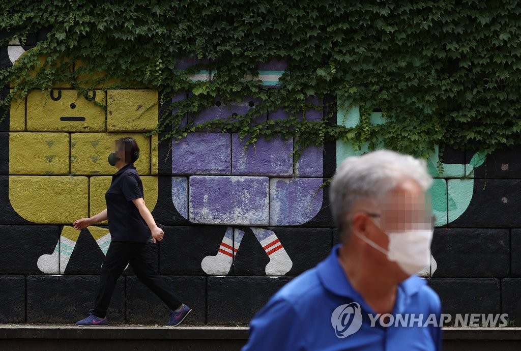 资料图片：7月5日，在首尔清溪川边，市民们戴着口罩散步。 韩联社