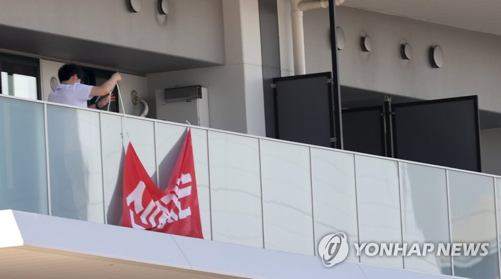 7月17日，在位于东京晴海地区奥运村的韩国代表团住宿区，韩国奥运代表团相关人员正取下“争议”横幅。 韩联社