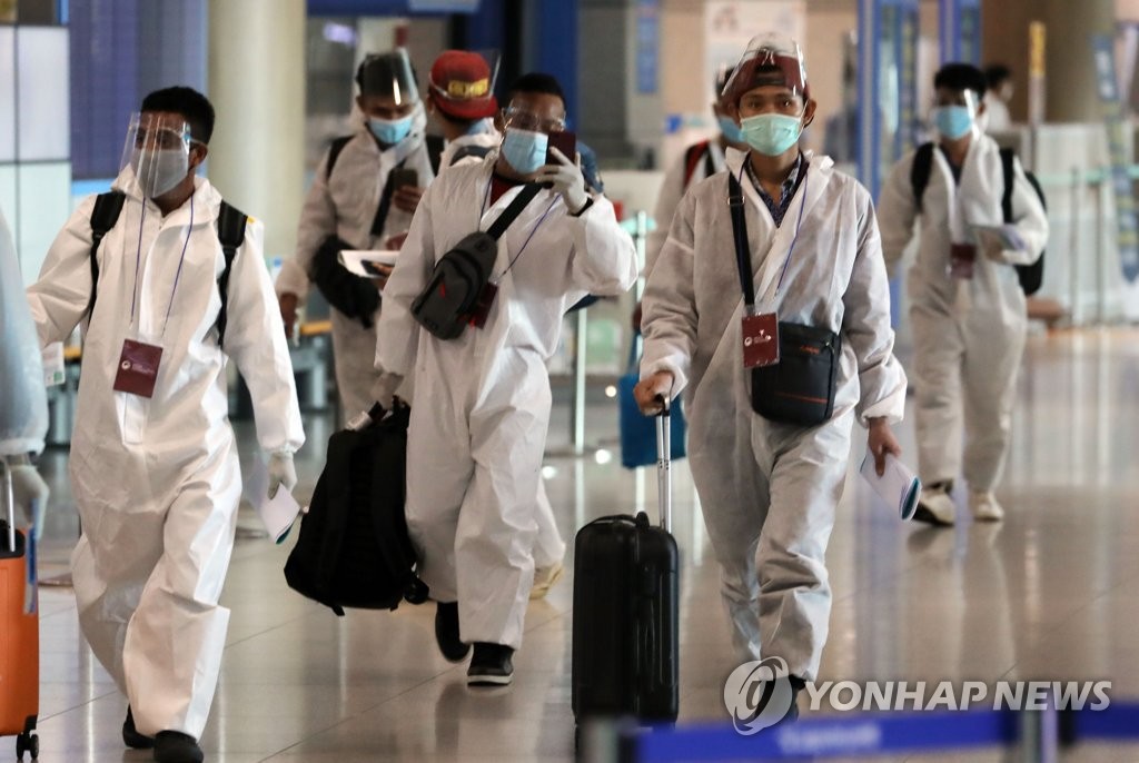 资料图片：身穿防护服的外籍旅客 韩联社