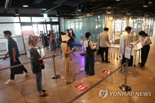 7月21日，在国立现代美术馆，“韩国美术名作——李健熙捐赠藏品特展”揭幕。图为访客在进入展场之前测体温并填写出入登记表。 韩联社