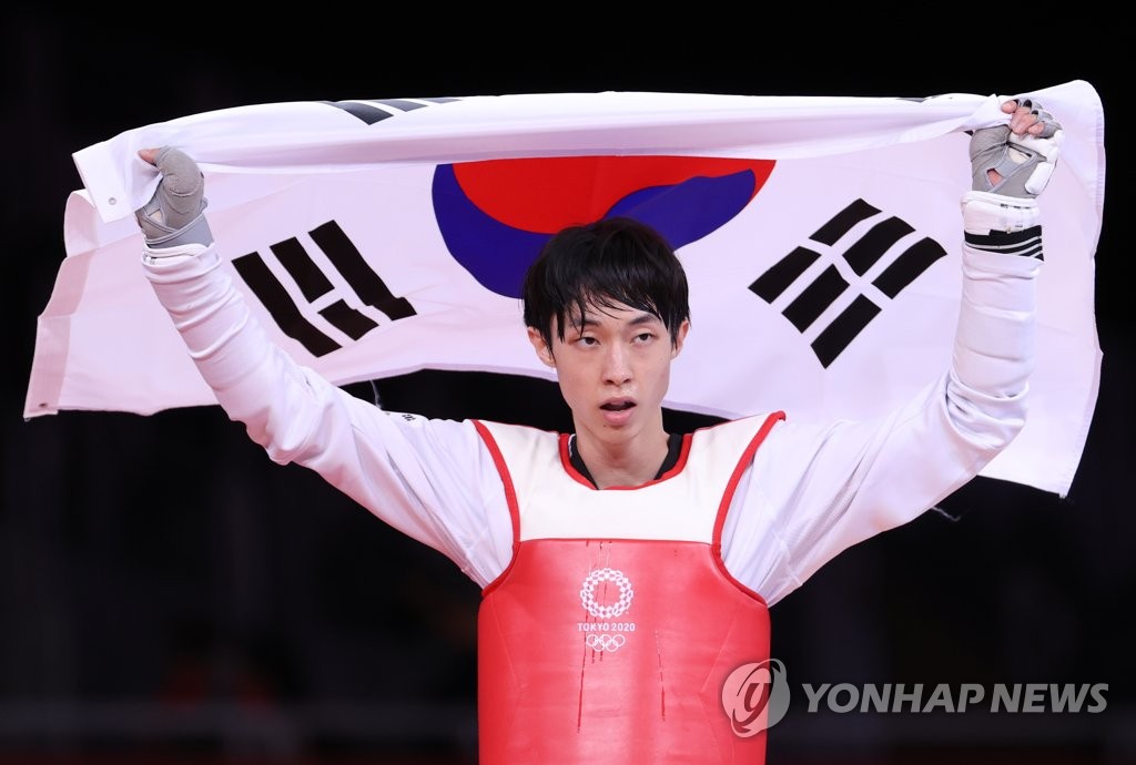 7月24日，在东京幕张展览馆，韩国跆拳道运动员张准夺得男子58公斤级铜牌后高举国旗庆祝。 韩联社