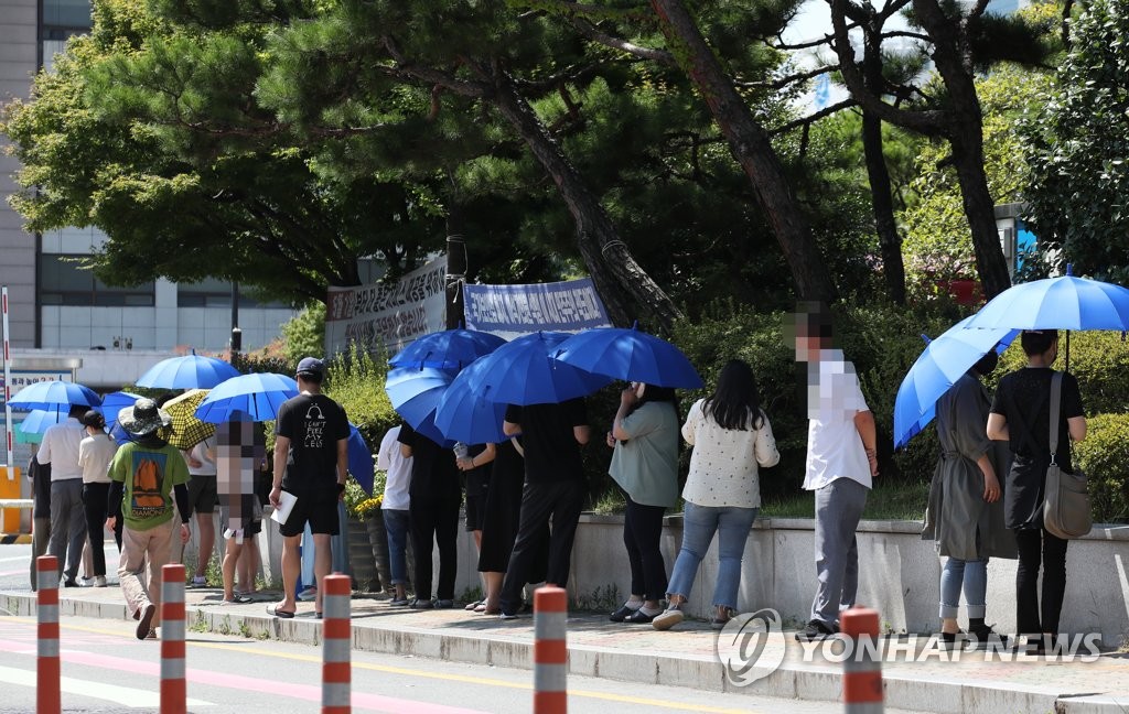 资料图片：在一处临时筛查诊所，市民排队候检。 韩联社