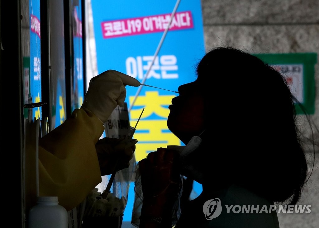 资料图片：8月3日，在首尔恩平区旧摆拨站临时筛查诊所，一位市民正在接受新冠病毒核酸检测采样。 韩联社