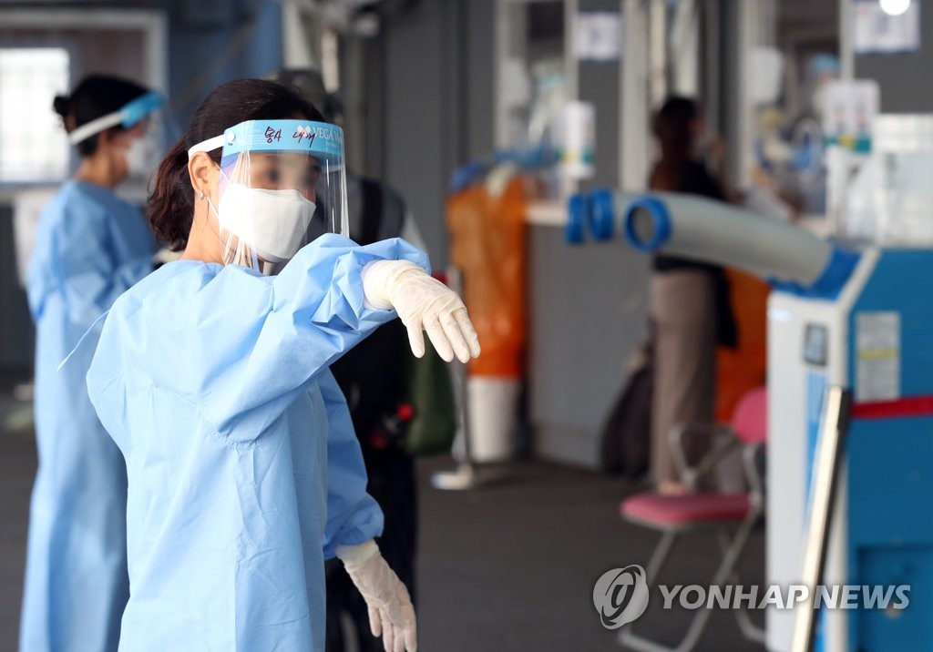 资料图片：8月7日，在首尔站临时筛查诊所，一名医务人员引导市民接受新冠病毒检测。 韩联社