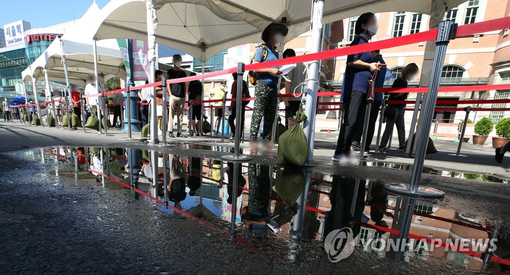 资料图片：8月7日，在位于首尔中区的首尔站临时筛查诊所，市民们排长队候检。 韩联社