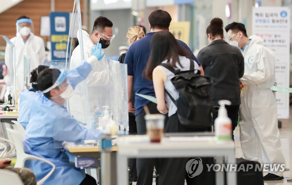 资料图片：8月8日，在仁川国际机场第二航站楼，防疫工作人员为入境者提供指引。 韩联社