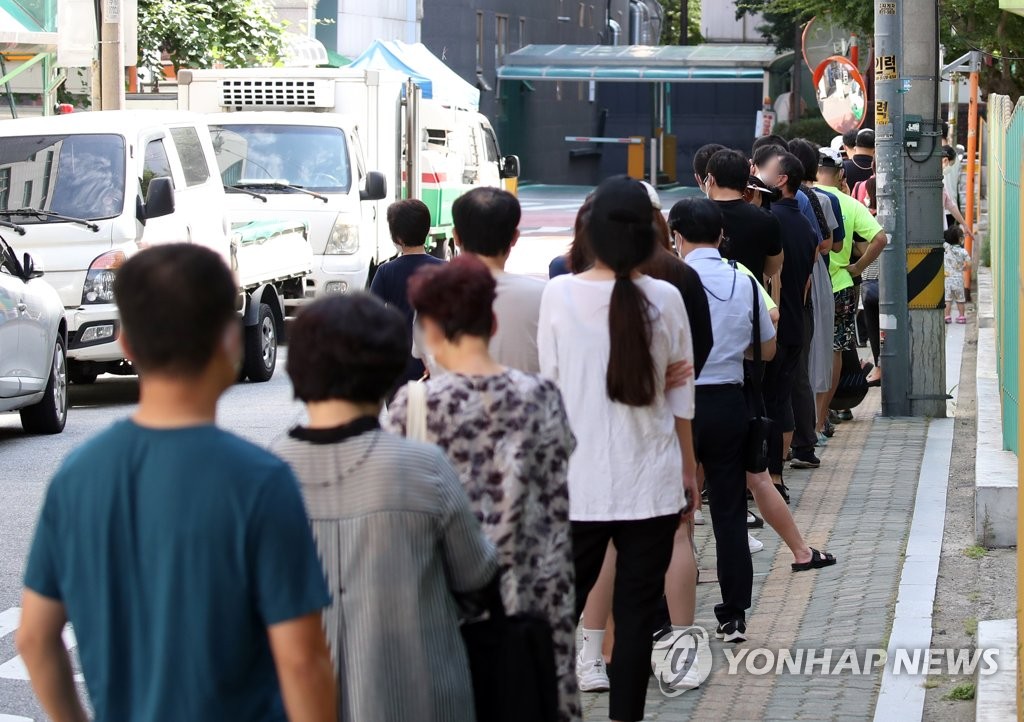 资料图片：在一处新冠筛查诊所附近，市民排队待检。 韩联社