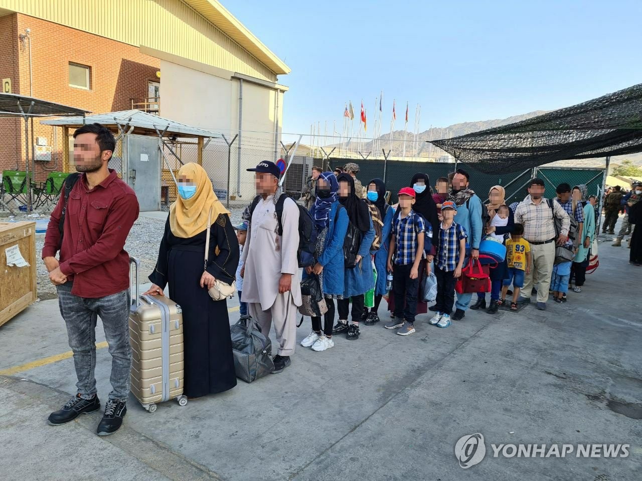 资料图片：当地时间2021年8月24日，在喀布尔机场，曾协助韩国政府的阿富汗人员排队搭乘韩国空军运输机。 韩联社/外交部供图（图片严禁转载复制）