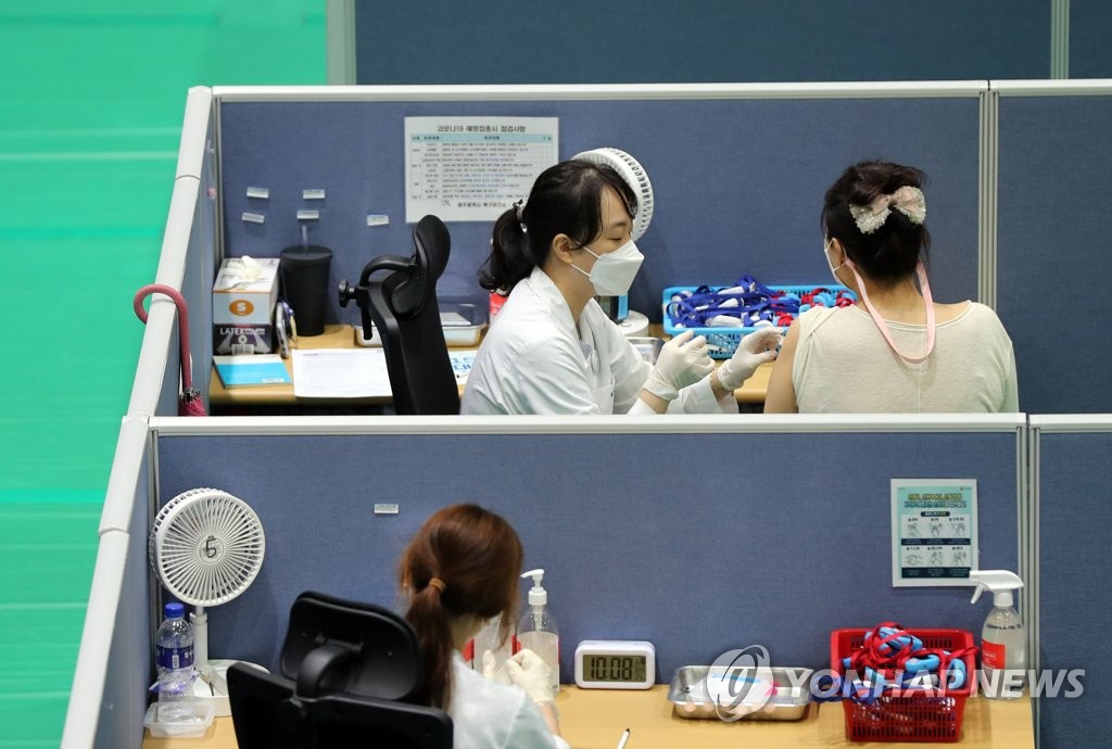 资料图片：在新冠疫苗接种点，医务人员为市民接种疫苗。 韩联社