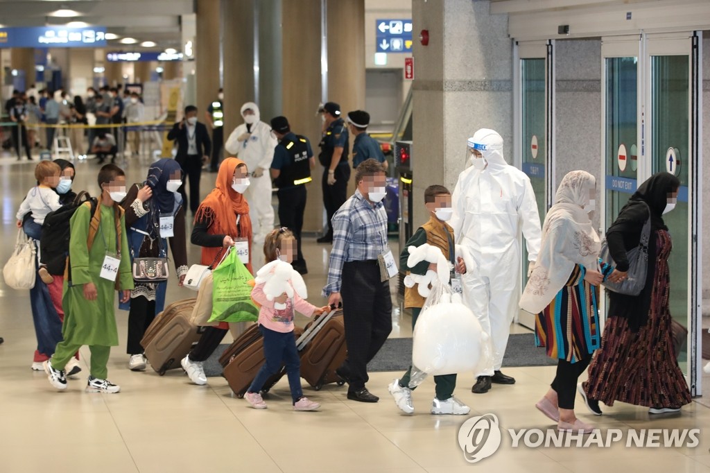 8月26日，在仁川国际机场，曾协助韩国政府活动的阿富汗人及其家属乘坐韩国空军多功能空中加油运输机。图为他们在接受核酸检测后，按照工作人员的指示走出机场。 韩联社