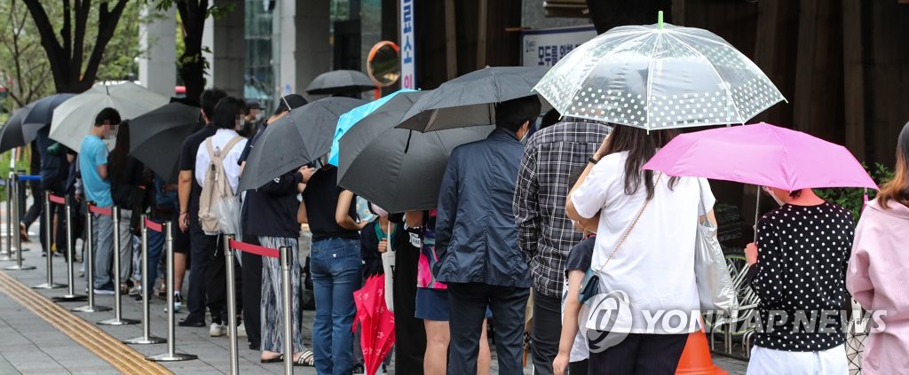 资料图片：9月7日，在设于首尔松坡区卫生站的筛查诊所，市民们撑伞排队等待接受病毒检测。 韩联社